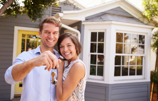 couple with keys standing outside new home